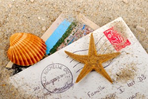 a postcard, starfish and seashell on a sandy beach