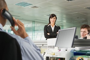 Business woman standing in the middle of a busy office