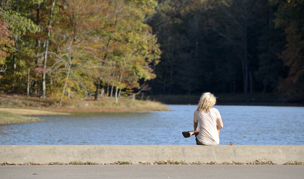 Woman sitting alone next to a lake